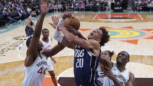 Dallas Mavericks forward Kessler Edwards (20) is blocked by San Antonio Spurs forward Harrison Barnes (40) as he drives to the basket during the first half of an NBA basketball game in San Antonio, Wednesday, March 12, 2025. (AP Photo/Eric Gay)