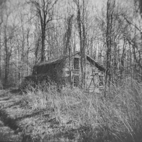 Photo of an old abandoned house taken with a Holga 120N "toy" camera.  The camera is about as cheaply made as possible with no seals to keep the light out, a plastic lens that varies in (non)quality from camera to camera and yet takes photos that would be hard to duplicate with any other camera.  The lens gives this house a creepy factor greater than it already has.