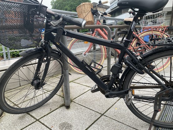 Ein schwarzes Fahrrad in einem öffentlichen fahrradständer. Für mich sind keine gravierenden Dreckspuren erkennbar