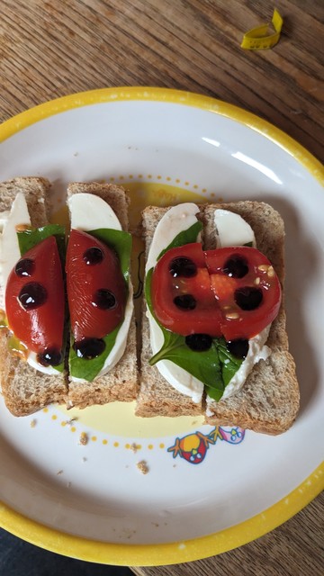 Auf einem Brot gestapelt: Mozzarella, Tomate und Basilikum bilden mit Balsamico einen Marienkäfer
