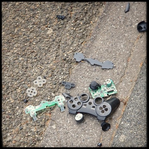 destroyed playstation controller on tarmac