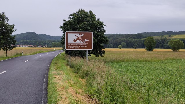 Landschaft mit Straße, Landwirtschaft, Bäumen und einem großen Schild mit Europakarte und der Aufschrift 