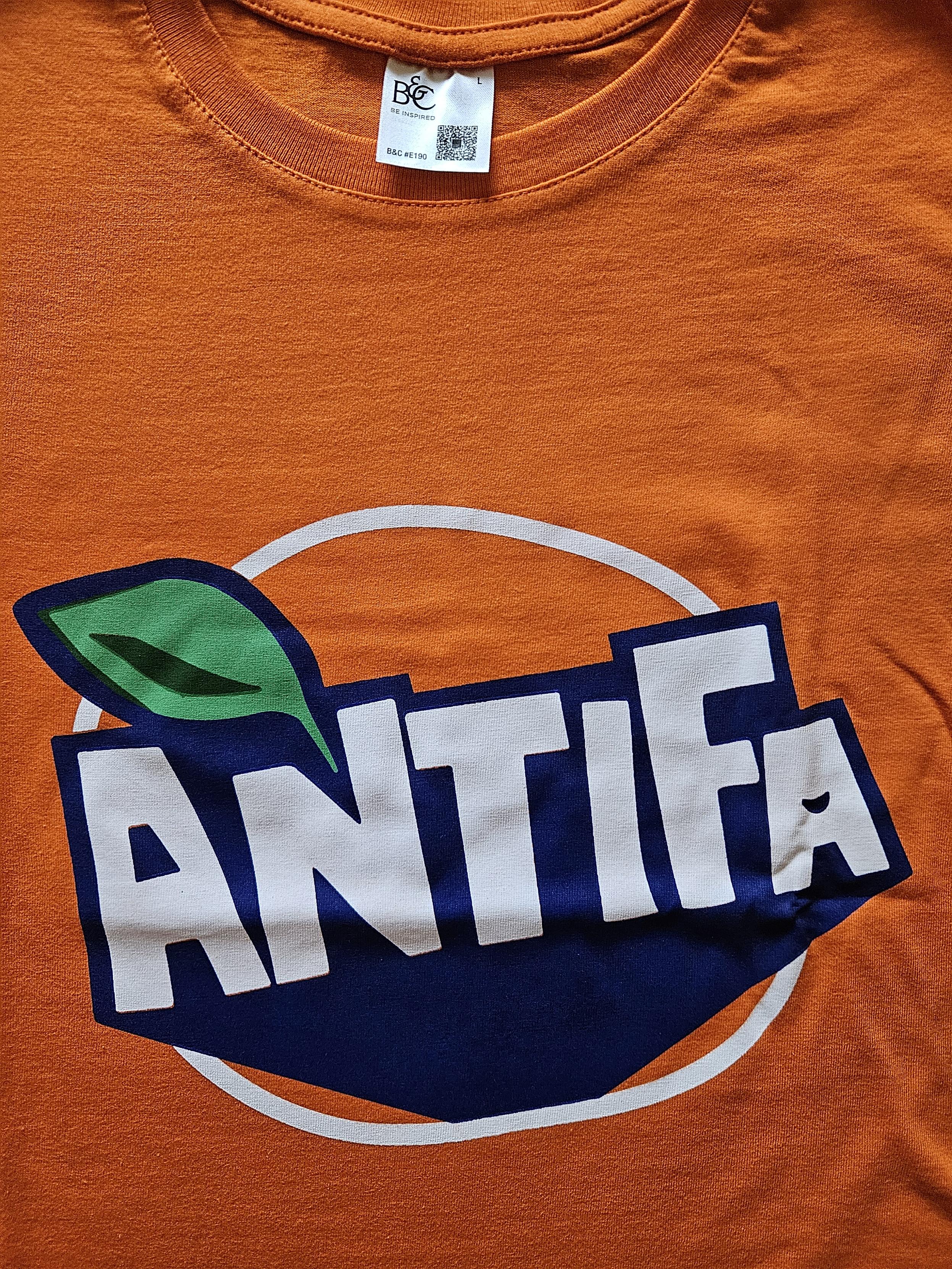 T-Shirt in orange mit dem Schriftzug
ANTIFA und einem grünen Blatt.

Design in Anlehnung an das Logo einer bekannten Orangenlimonade.