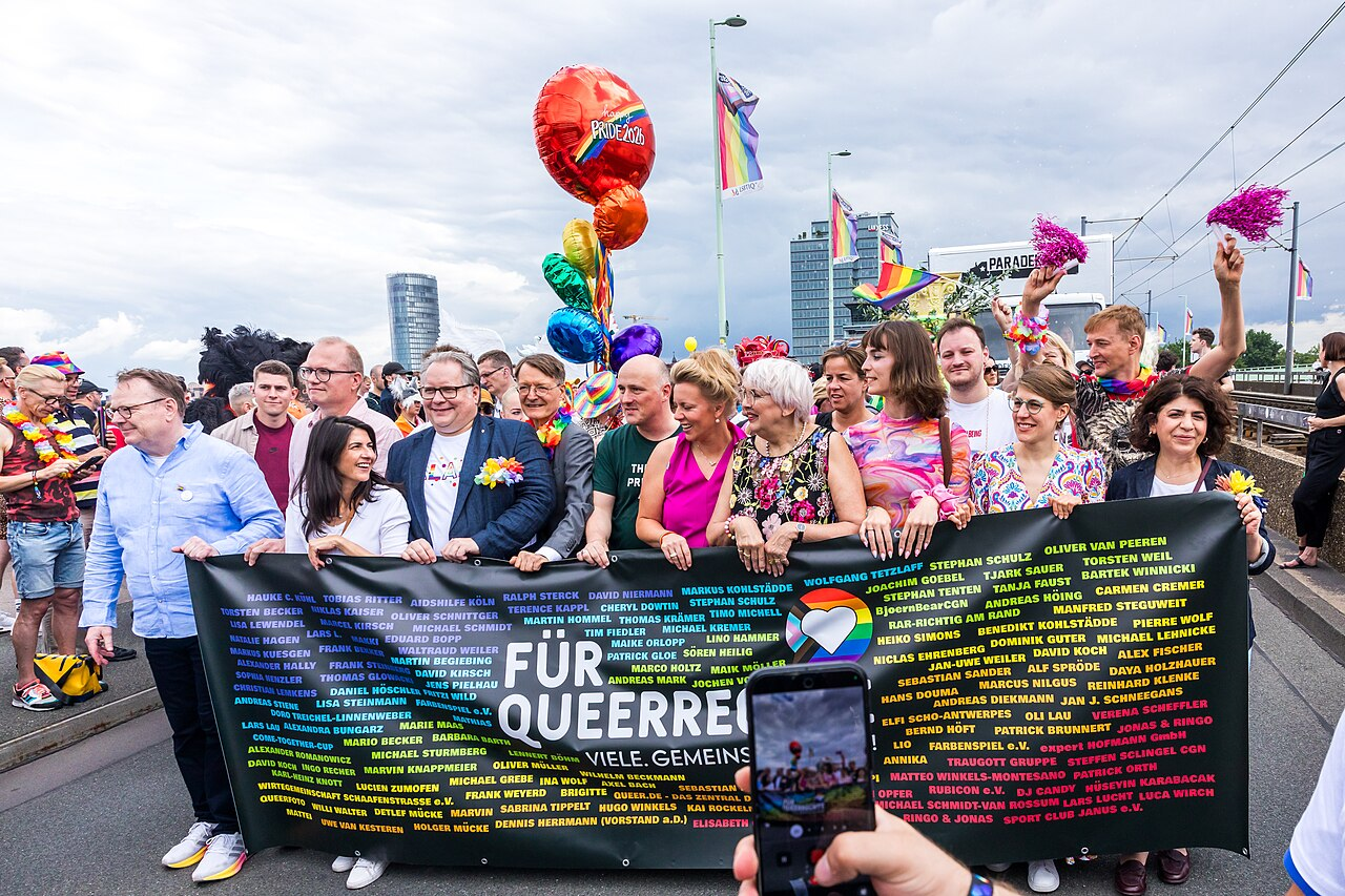 Personen zu Beginn der Cologne Pride-Demo: OB Torsten Burmester, Jochen Ott, Serap Güler, Lutz Schade, Karl Lauterbach, Sven Lehmann, Ina Brandes, Claudia Roth, Mona Neubaur, Nyke Slawik, Verena Schäffer, Berivan Aymaz (Parteien und Ämter siehe Wikipedia). Sie alle halten ein großes, schwarzes Banner, auf dem das Motto der Parade steht: Für Queerrechte

© Raimond Spekking / CC BY-SA 4.0 (via Wikimedia Commons)