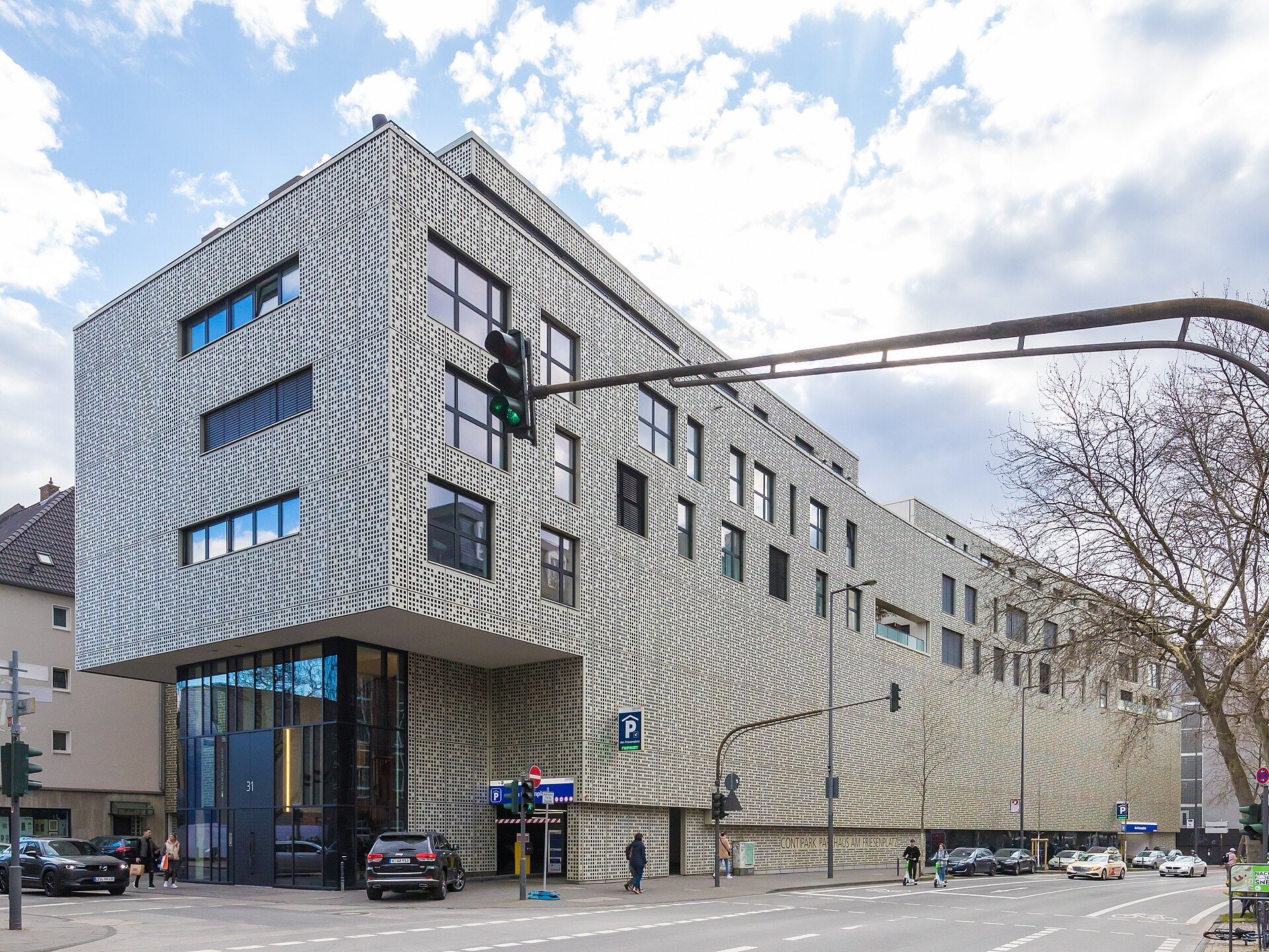 Schrägansicht auf ein um 3 Stockwerke aufgestocktes Parkhaus. Die Fassade besteht aus weißen Lochblechen.
