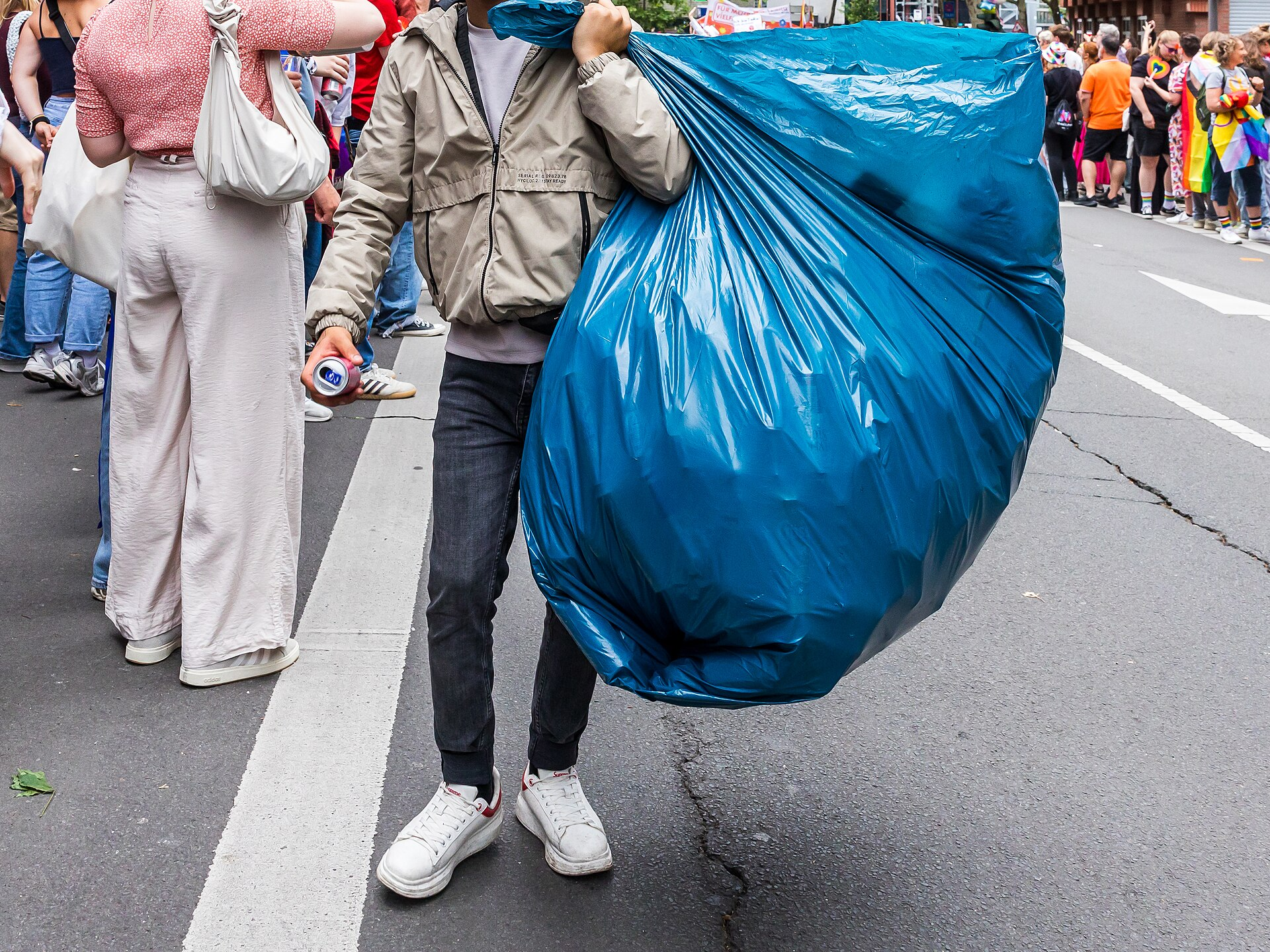 Ein Mann trägt einen sehr großen blauen Sack mit Pfandflaschen
