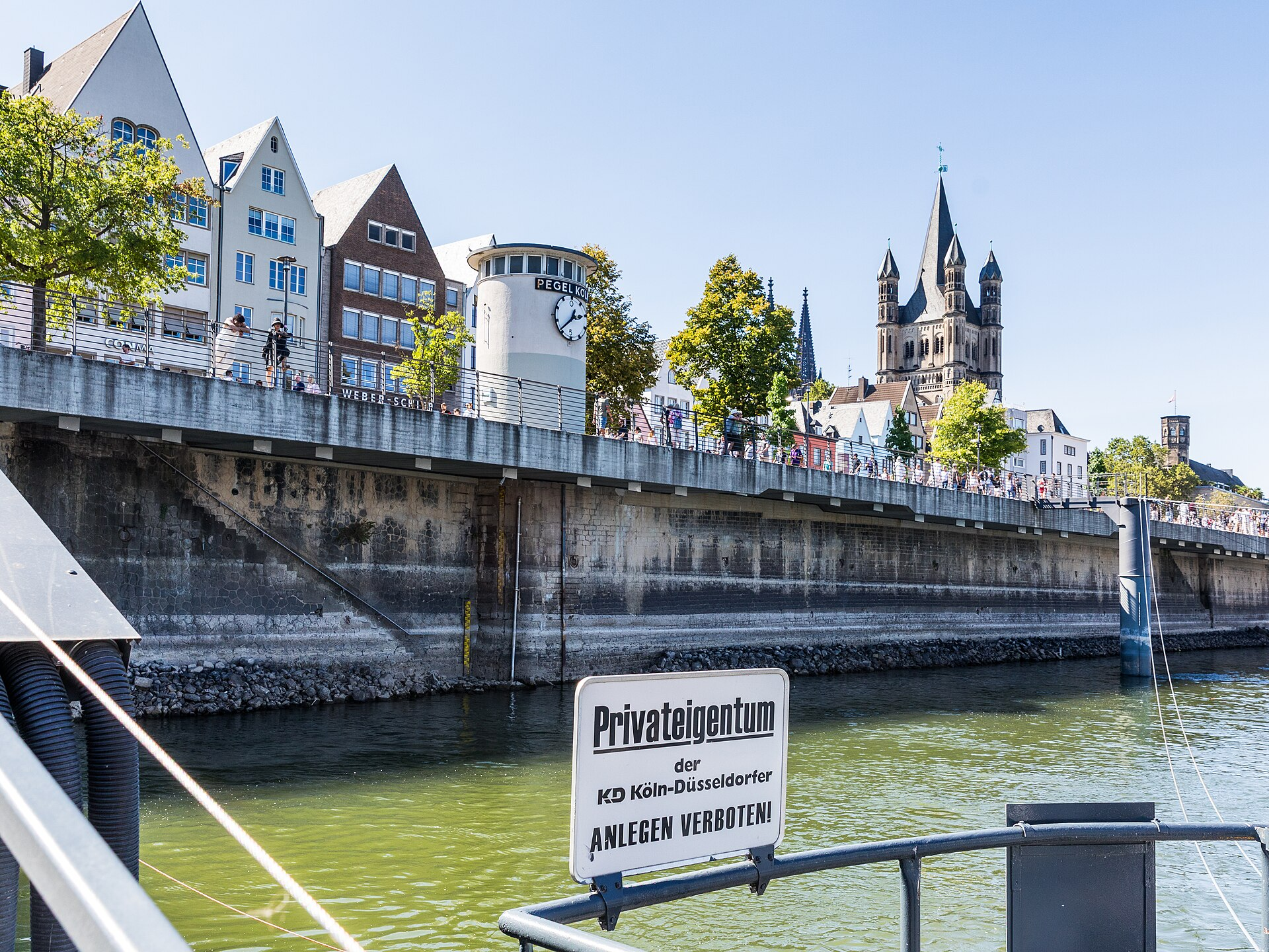 Blick von einem Steiger in Richtung Ufer in der Kölner Altstadt mit dem Pegel Köln